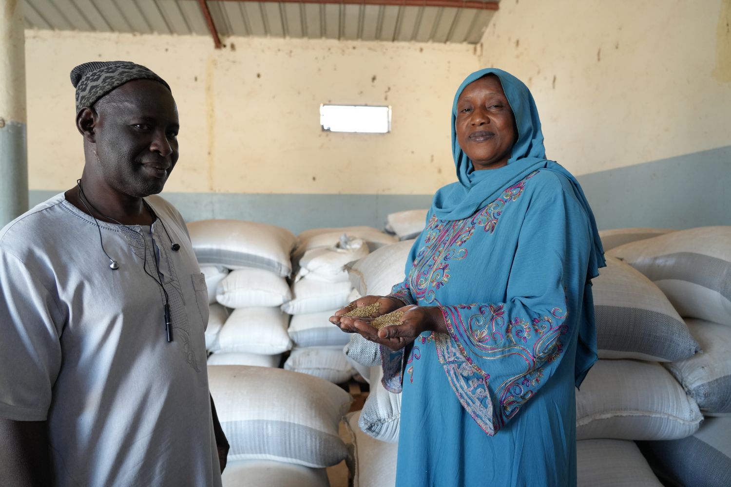 A man and a woman standing in front of sacks of grain