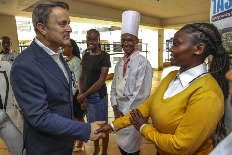 Un homme en costume serrant la main à une femme avec un pull jaune